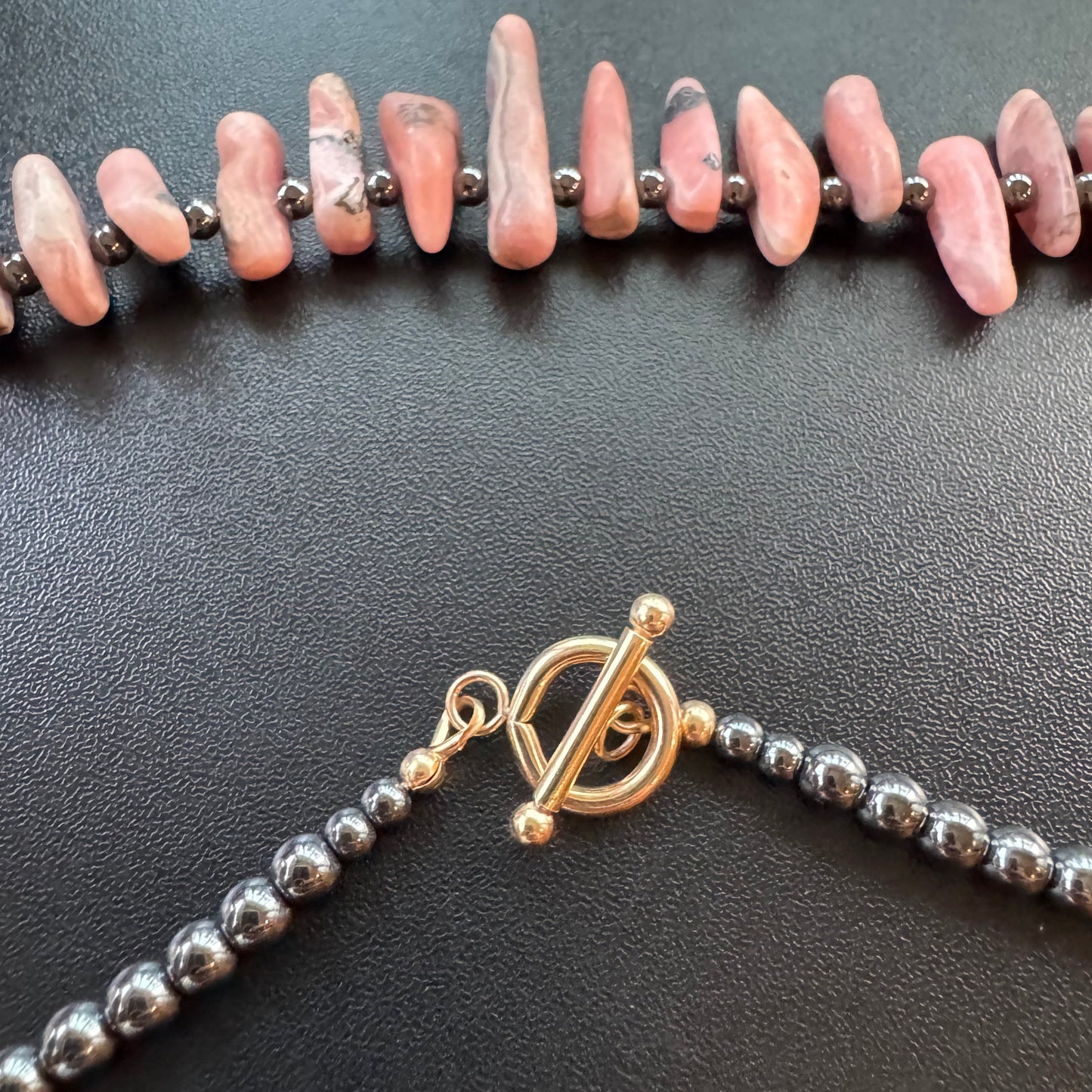 Necklace with pink stones, gold clasp, and shiny hematite beads