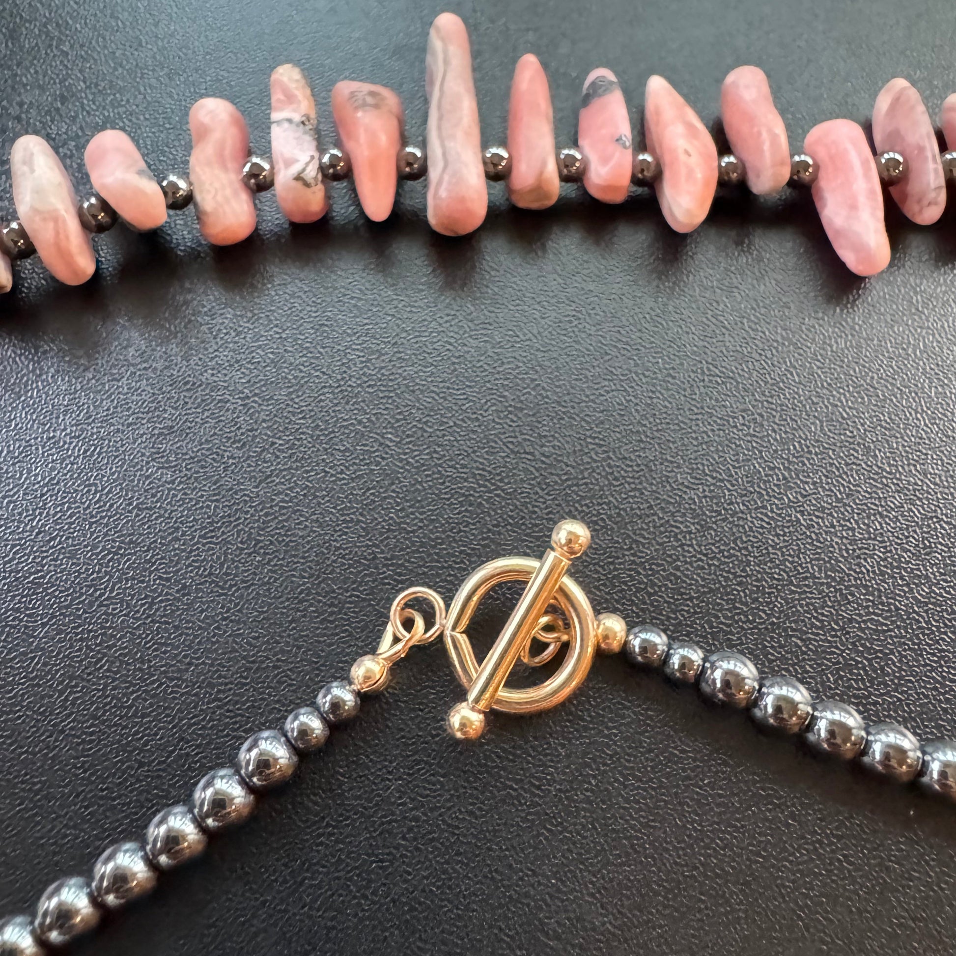 Necklace with pink stones, gold clasp, and shiny hematite beads
